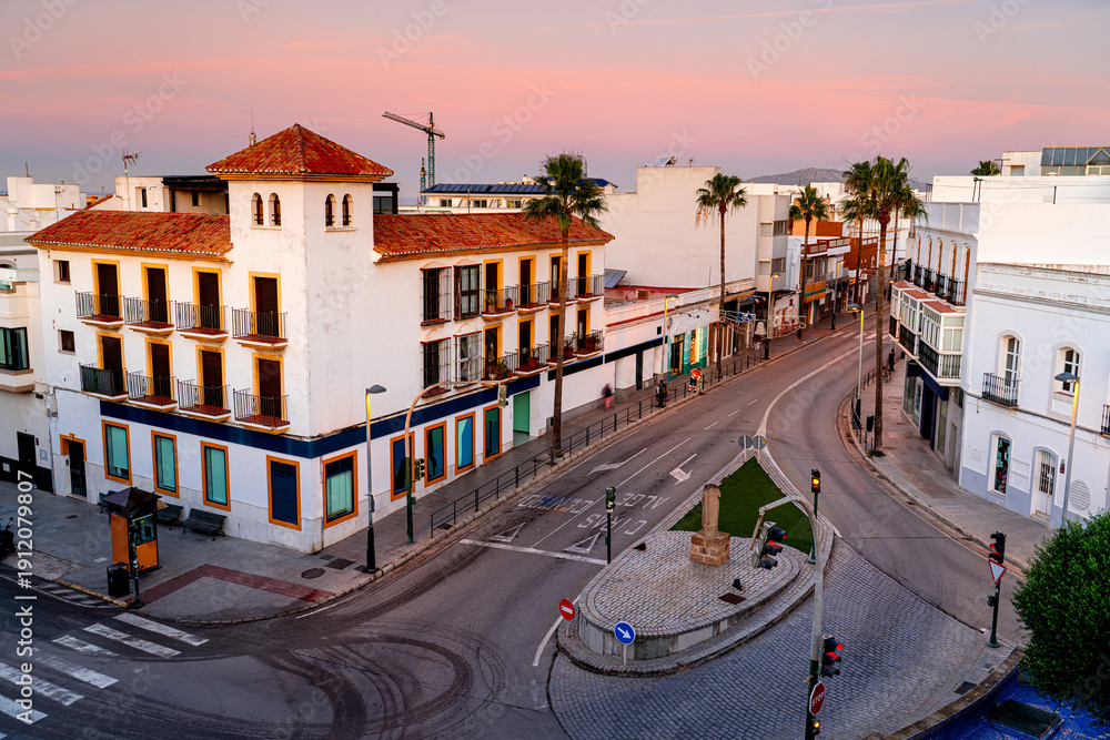 Obraz premium Crossing a street without people with palm trees and traditional houses at sunrise, Spain, Tarifa.