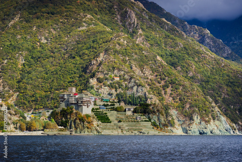 Картината върху платно Coastal landscape showing Dionysiou Monastery dramatically built on rocky slopes of Mount Athos, Greece, with green mountains and the deep blue Aegean Sea