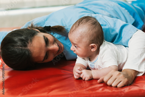 Obraz na plátně Physiotherapist interacting with a baby lying in prone position during rehabilit