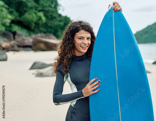 Photography Portrait of a young woman surfing at the beach, holding surfboard, ocean waves,