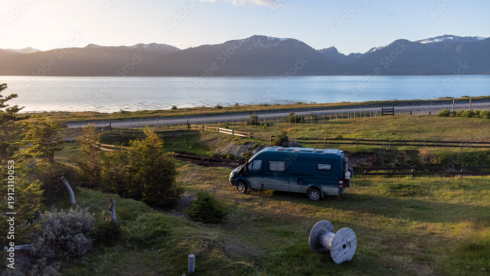 Fototapeta premium Van Life Adventure: Drone Shot of Camper Van by Snowy Mountains and Sea