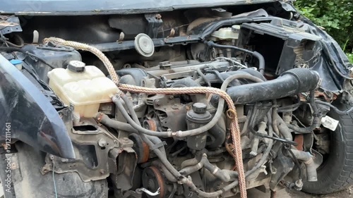 The car was seriously damaged as a result of a recent collision and a traffic accident. Close-up of car engine shows a extensive damage to the front as a result of a serious accident.
