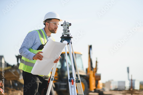 Foto Surveyor engineer supervising construction site with leveling equipment