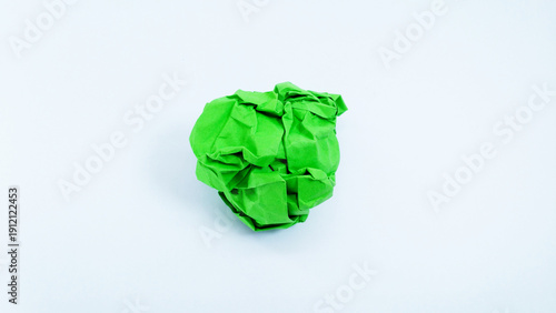 Close up of a vibrant green crumpled paper ball, symbolizing a discarded idea, mistake, or creative block, isolated on a clean white background. Concept of brainstorming, frustration, and recycling.