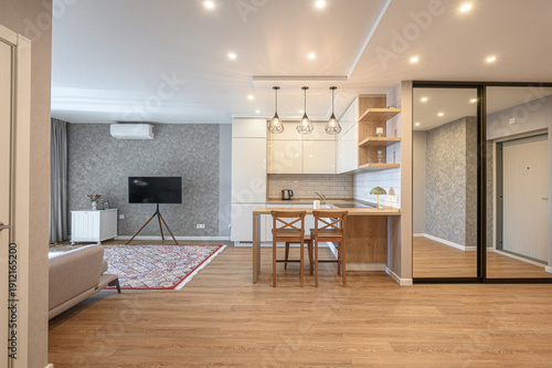 Billede på lærred A modern studio with light wood flooring, beige sofa, patterned rug, TV on tripo