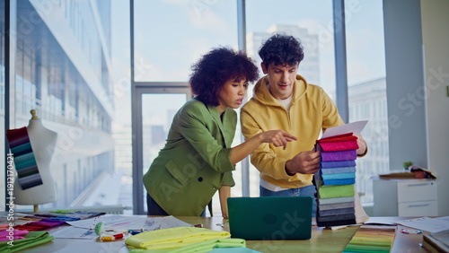 Couturiers selecting cloth samples for fashion clothing in creative agency.