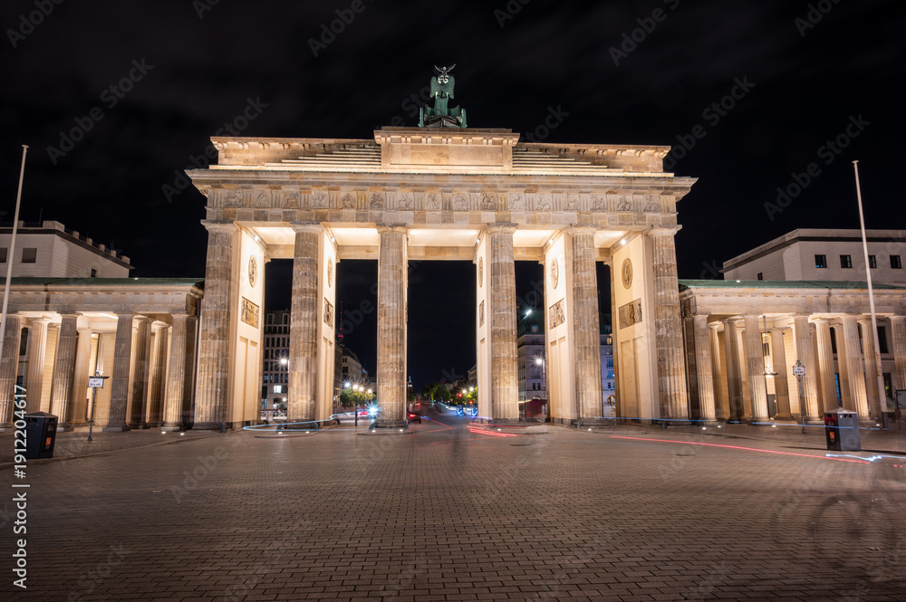 Obraz premium Berlin, germany, august 13, 2023. Brandenburg gate in glowing against the night sky, neoclassical monument and symbol of german unity and history, empty street