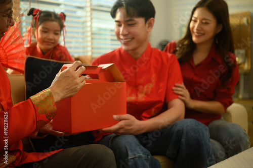 Spring Festival moment as son and daughter-in-law offer a festive gift, symbolizing gratitude, blessings, and reunion