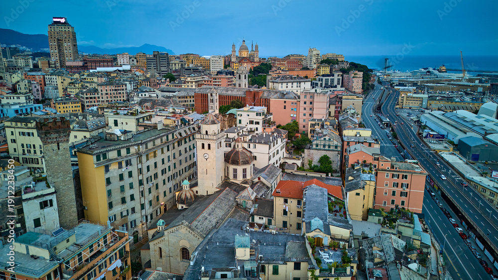 Fototapeta premium Drone view of Genoa's historic churches Santa Maria Assunta and Chiesa di Santa Maria di Castello and the elevated highway in Italy. An aerial shot of the city's diverse architecture by the sea.