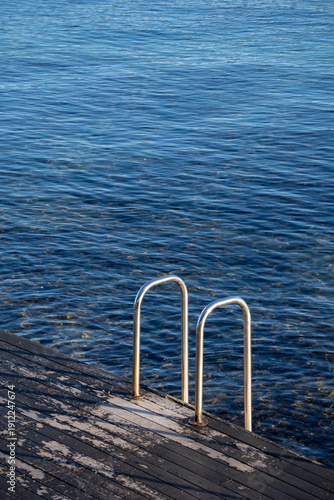 Swimming pool ladder leading into the sea from wooden platform