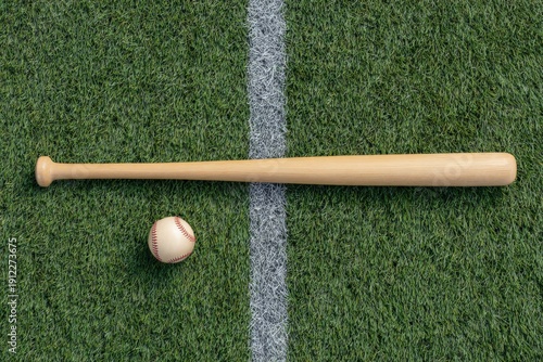 Wooden baseball bat and ball on grass field near foul line