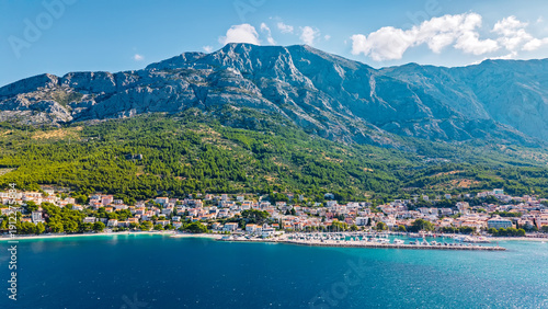 Foto Stunning Croatian coastal town nestled beneath dramatic mountain range with turq