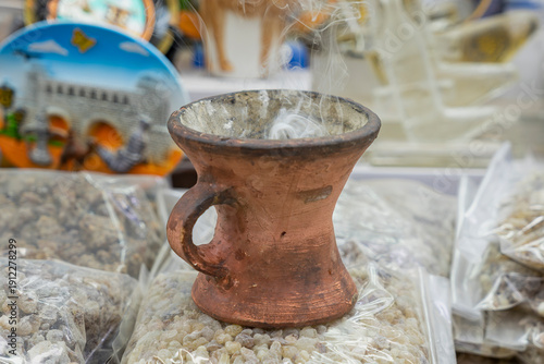 Foto close-up of a traditional clay frankincense burner (majmar) releasing wisps of smoke in a Salalah market