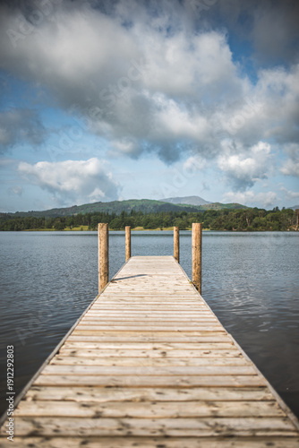 Wallpaper Mural Wooden pier extending into a calm lake with forested hills and cloudy sky Torontodigital.ca