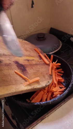 Chef putting sliced vegetables into a cooking pan