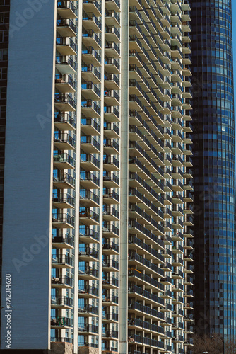 City buildings stand close to each other in a modern area, showcasing tall structures with balconies during a sunny day