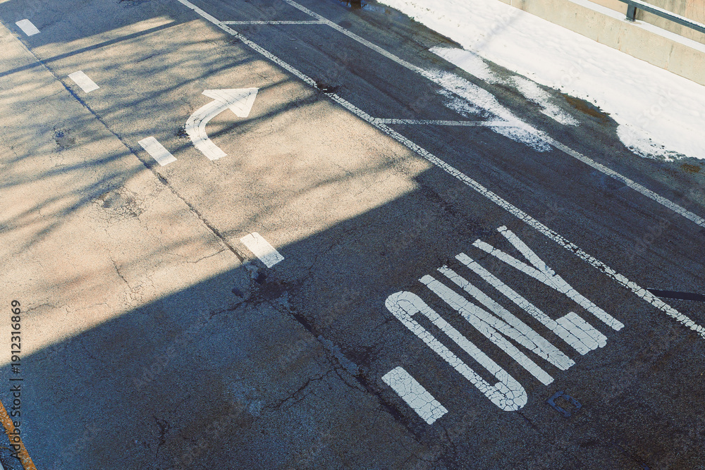 Fototapeta premium Road marked for one-way traffic with a left turn option at a city intersection during daytime