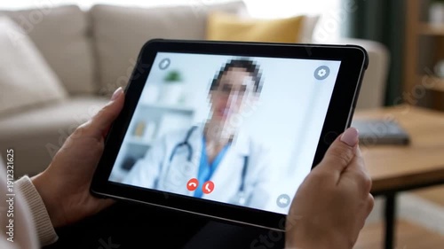 Close-up of hands holding a tablet for a telemedicine consultation with a doctor on screen