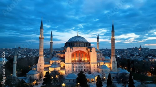 Majestic Hagia Sophia mosque in Istanbul at dusk with dramatic clouds and city lights below