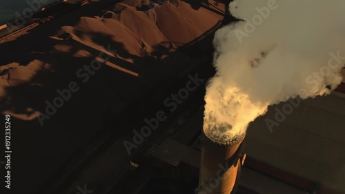 Industrial smokestack releasing thick toxic coal smoke at sunset. Factory emits harmful emissions into the air. Fossil fuel pollution, industrial air contamination, and environmental damage concept.