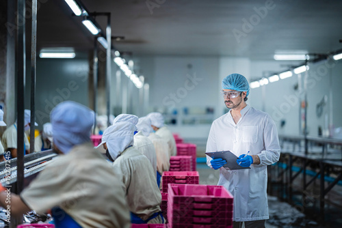 Obraz na plátne A worker in orange gloves sorts fresh, raw fish on an industrial production line