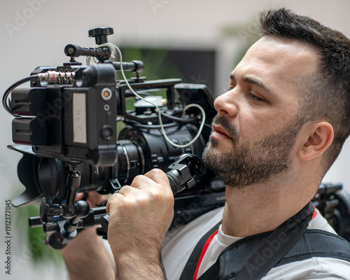 Valokuva A male videographer holding a heavy professional cinema camera rig on his shoulder, ready for filming