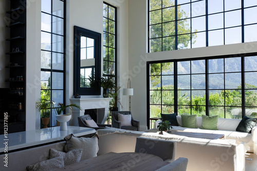 Light L-shaped sectional sofa is anchoring sunlit living room with coffee table, fireplace, plants