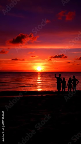 Sunset over the ocean with silhouetted figures strolling along the beach at dusk.
