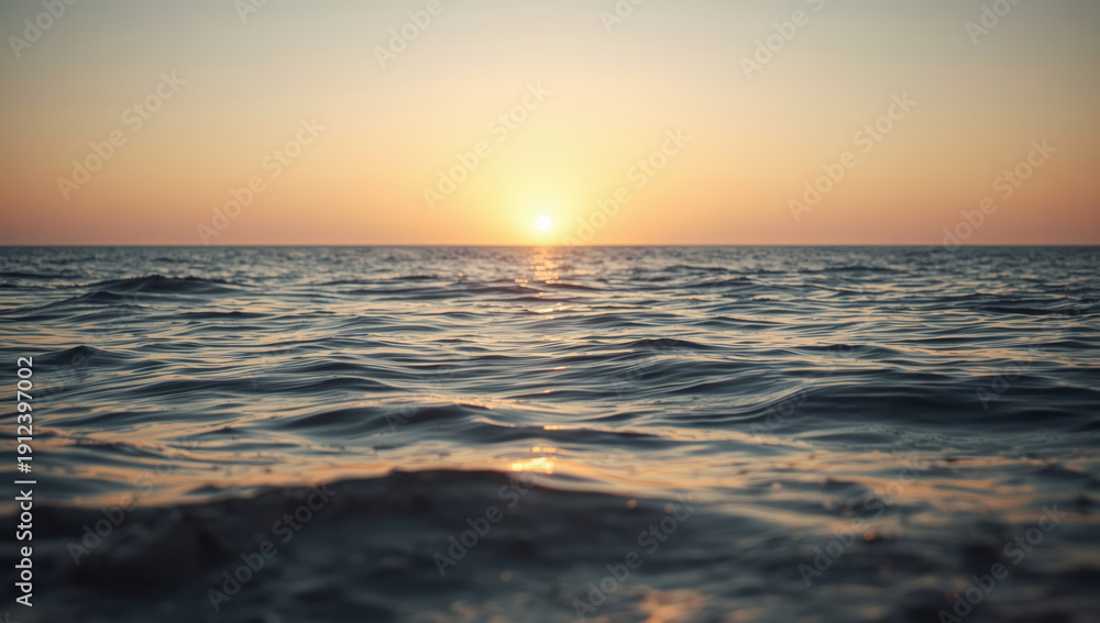 Obraz premium Calm sea sunset with gentle waves and warm sky glow
