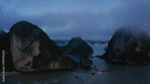 Serene twilight panorama of misty limestone karsts and tranquil ocean waters with moored boats