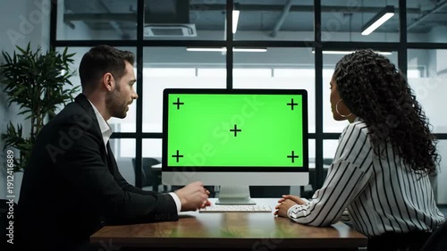 Diverse business colleagues discuss project on green screen computer monitor in modern office meeting