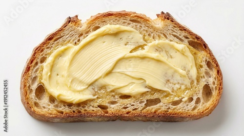 Slice of crusty artisan sourdough bread thickly spread with butter, top view isolated on white background