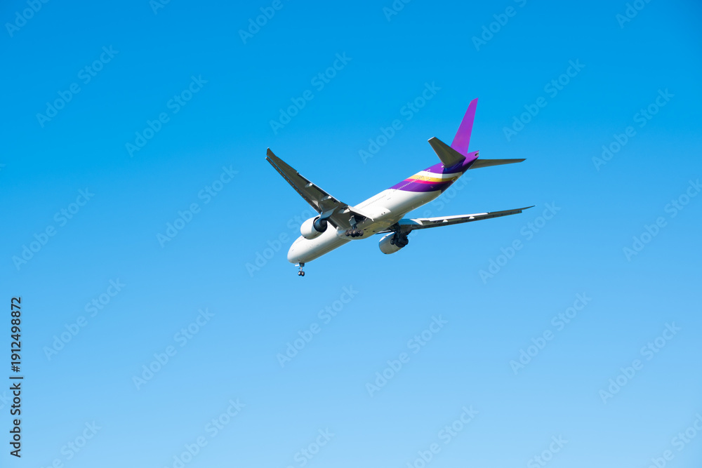 Obraz premium Passenger aircraft with landing gear down, flying in a bright blue sky. on the engines and tail, perfect for travel and transportation concepts. 