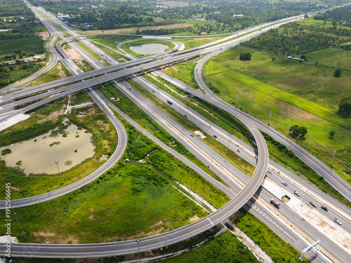 Drone shot a large highway interchange crossing over green farmlands in Thailand