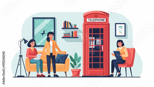 Women collaborate near a telephone booth in a modern office setting