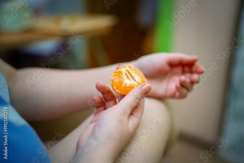 Wallpaper Mural Girl's hand holding a small piece of peeled mandarin. Fresh citrus snack moment. Torontodigital.ca