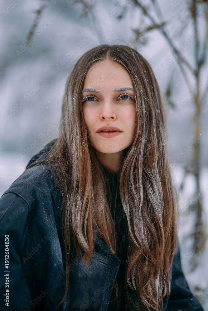 Naklejka premium A striking portrait of a brunette woman completely covered in delicate frost . Her eyelashes, eyebrows, hair, and clothing are intricately frosted.