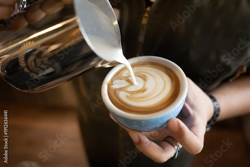 Картината върху платно Latte coffee milk foam art barista cup pour creamy swirl forms in blue ceramic,