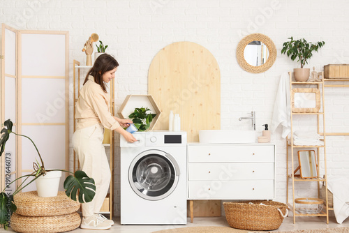 Young woman putting laundry...