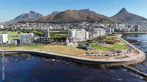 Drone flies from the sea over Green Point toward base of Signal Hill on a sunny day in Cape Town, South Africa