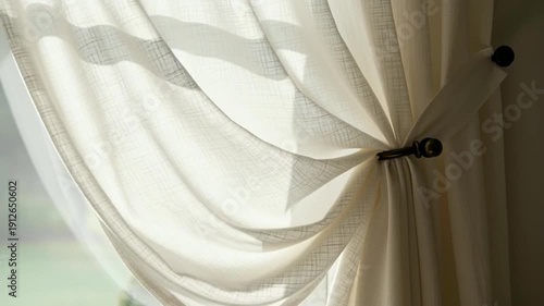 Soft light filtering through sheer cream curtains tied back from a window, garden view