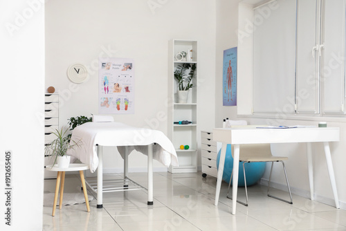 Interior of massage therapist's office with workplace, couch and shelving uni...