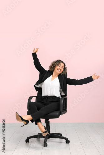 Mature businesswoman sitting on armchair on pink background