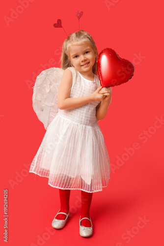 Cute little girl dressed as cupid with heart-shaped balloon on red background. Valentine's Day celebration