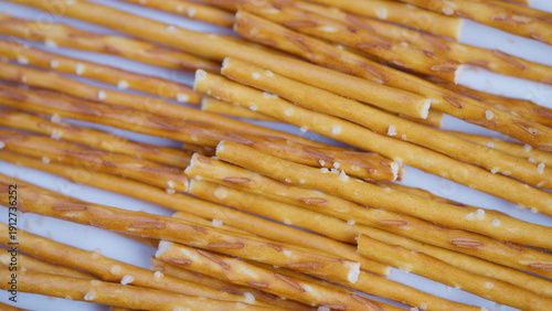 Salty pretzel sticks arranged neatly. Golden brown pretzels with visible salt crystals. Studio shot capturing salted pretzel sticks with crisp surface and appetizing appearance