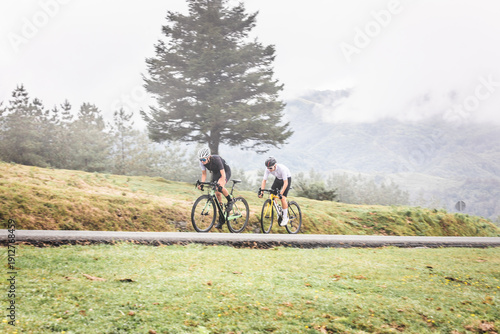 Cyclists man and woman couple riding together climbing a mountain at the Aiako Harriak natural park in the Basque Country.