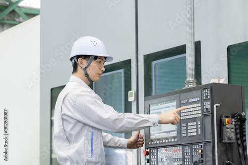 Foto 工場の操作盤の前で働く男性作業員