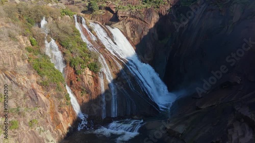 Ezaro Waterfall With Cascades Rushing Down Rugged Cliff In Galicia, Spain. aerial shot