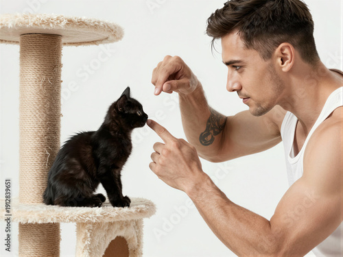 muscular tattooed man guiding tiny black kitten up cat tree, contrast of strength and gentleness in encouraging growth