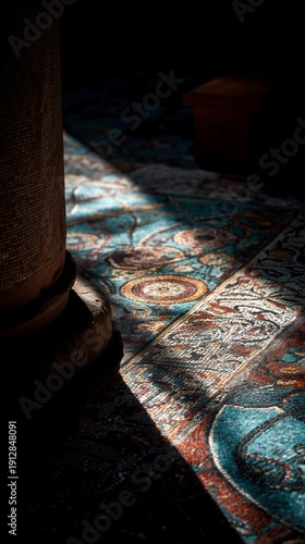 In a softly illuminated room, a vibrant, intricately woven rug catches the light, while a prominent column stands in the foreground, adding depth to the scene